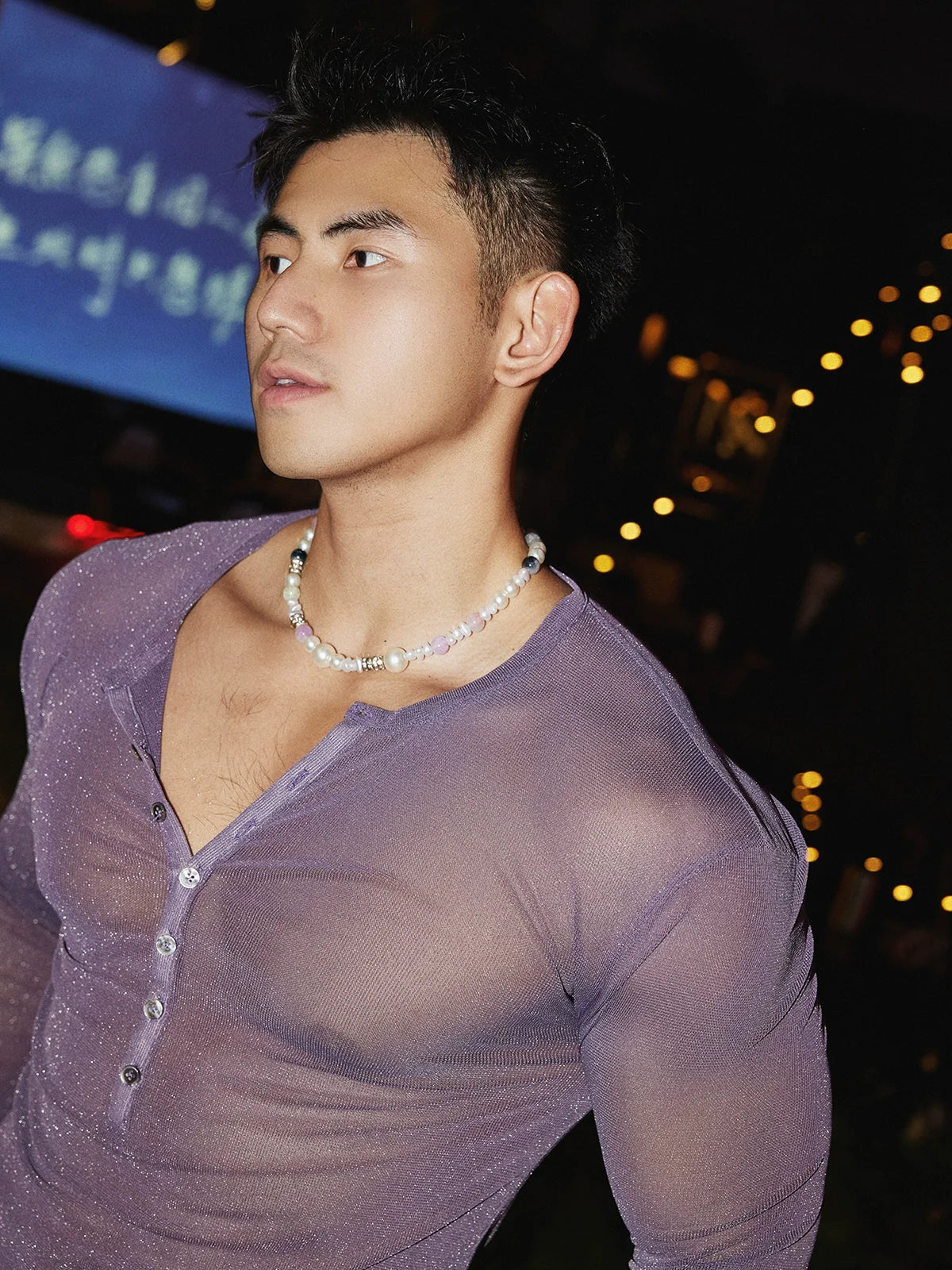 Man wearing a sheer purple shirt with a dark background